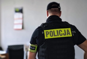 Policjant kryminalny stojący tyłem.