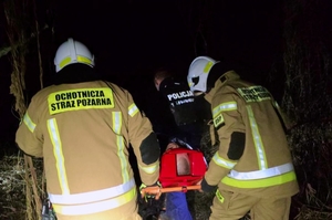 Funkcjonariusze transportujący mężczyznę na desce ratunkowej.