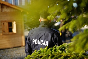 Policjant stojący przy choince.