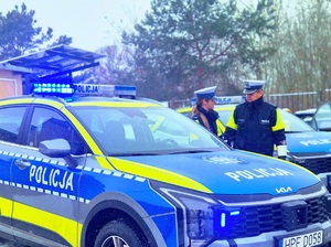 Policjanci przy radiowozach.