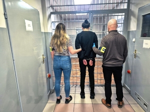 Policjanci podczas doprowadzenia zatrzymanej kobiety.