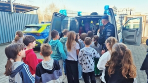 Dzieci z policjantami przy radiowozach.