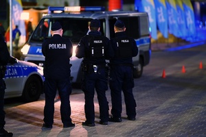 Policjanci przy radiowozach.