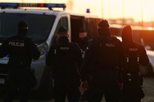 Policjanci przy radiowozach.