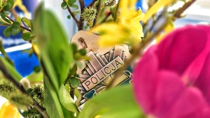 Napis policja na tle wiosennych kwiatów.