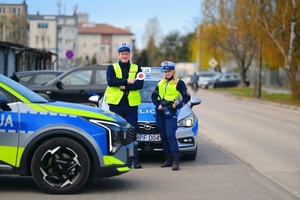 Policjanci ruchu drogowego przy radiowozie.