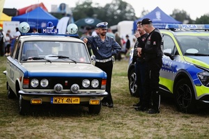 Policjanci przy radiowozach.