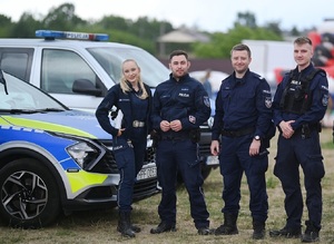 Policjanci przy radiowozach.