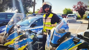 Policjant obok motocykla.
