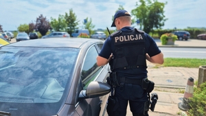 Policjant sprawdzający czy nikogo nie ma w aucie.