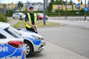 Policjant ruchu drogowego przy radiowozie.