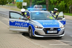 Policjanci wsiadający do radiowozu.