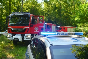 Radiowóz na tle wozów strażackich.