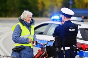 Policjanci rozdający kamizelki rowerzystom.