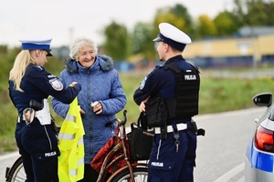Policjanci rozdający kamizelki rowerzystom.