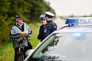Policjanci rozdający kamizelki rowerzystom.