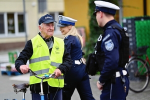 Policjanci rozdający kamizelki rowerzystom.
