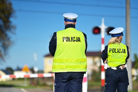 Policjanci a w tle przejazd kolejowy.