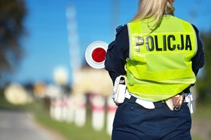 Policjantka a w tle przejazd kolejowy.